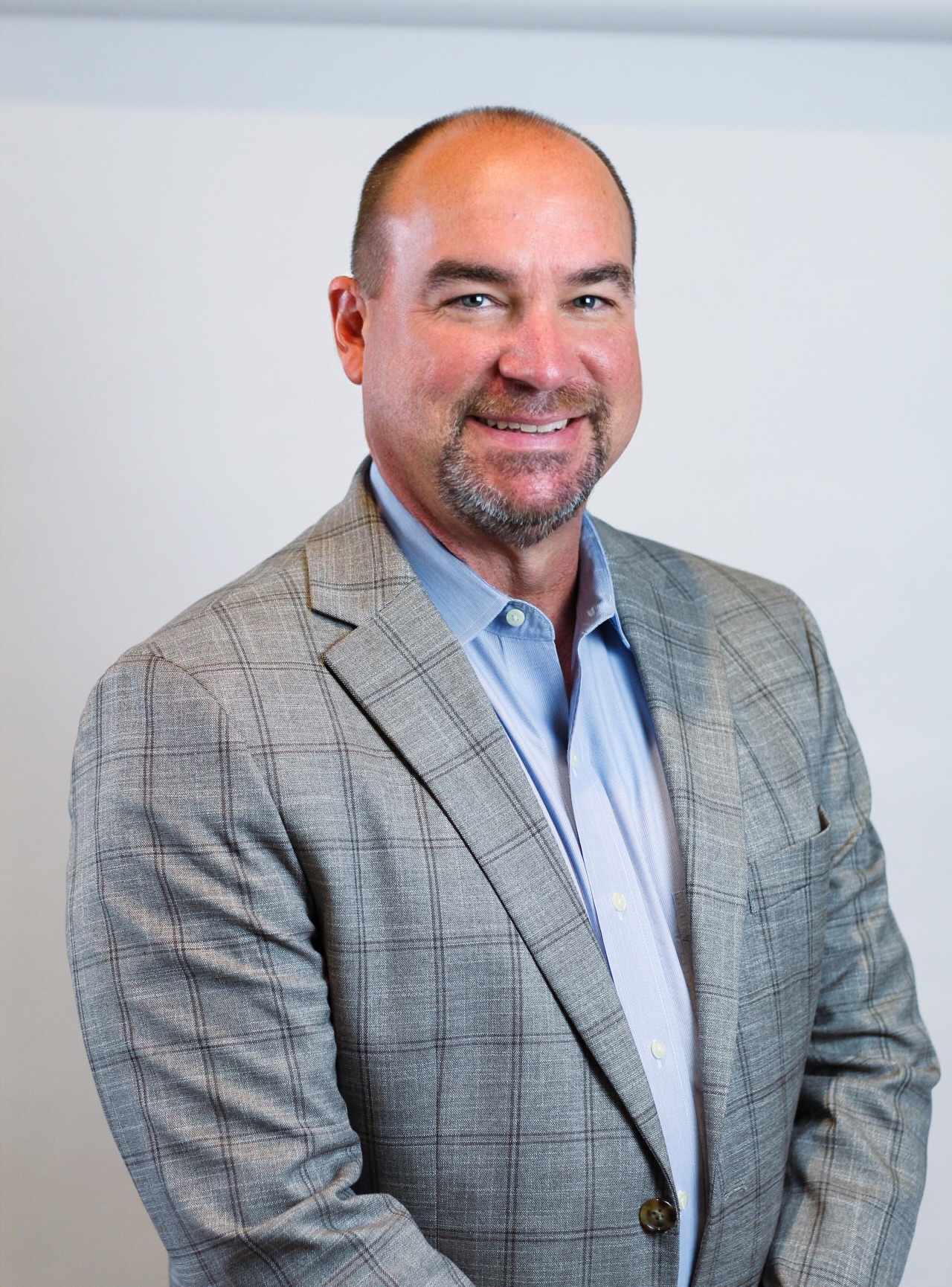 Business headshot of a man in a plaid sport coat